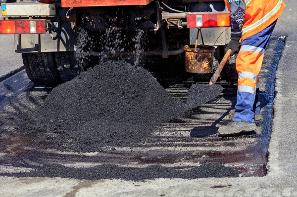 修路工人用铲子分发一块沥青路面修补 — 图库照片