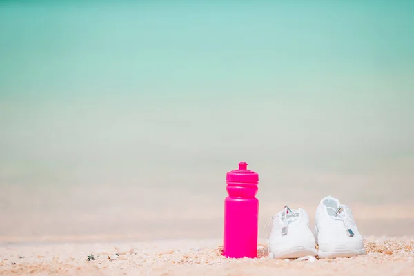 运动鞋和白色沙滩上的瓶子 — 图库照片
