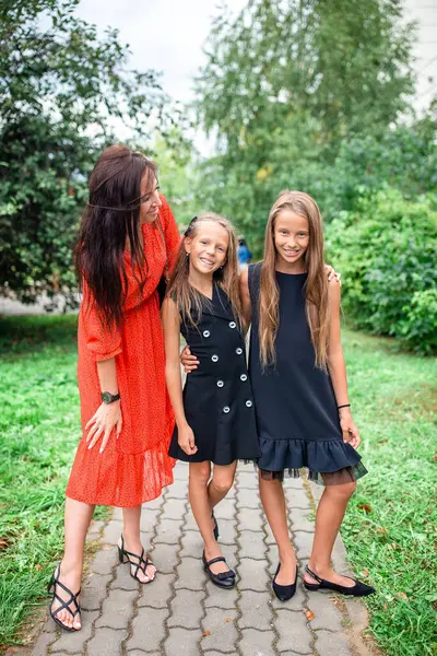 母と娘たちは学校へ行く 可愛い女の子は学校に戻ることに興奮しています — ストック写真