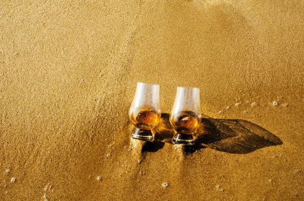 波に洗われた砂の上にウィスキーのシングルモルトが2杯 — ストック写真