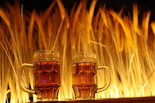 バックグラウンドの照明付きテーブル上のビールグラス — ストック写真