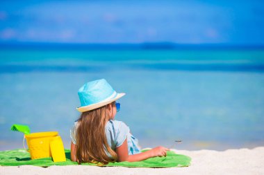 Yaz tatilinde elinde plaj oyuncaklarıyla şapkalı şirin bir kız.