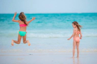 Küçük kızlar tatilde sığ sularda birlikte oynuyorlar.