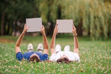 Rahat genç çift çim üzerinde yalan kitap okuma