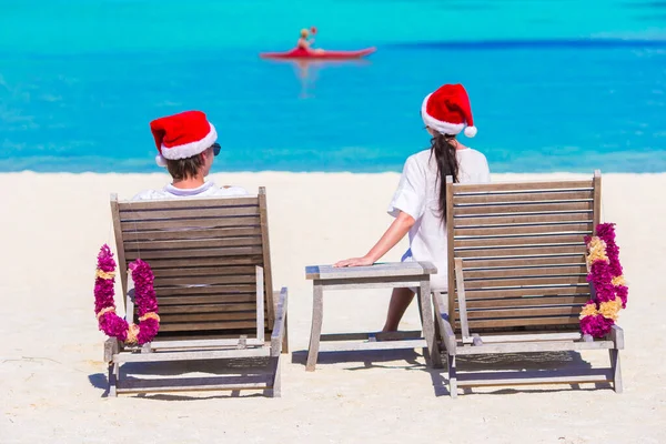 年轻的夫妇在圣诞假期的沙滩上放松的圣诞老人帽 — 图库照片