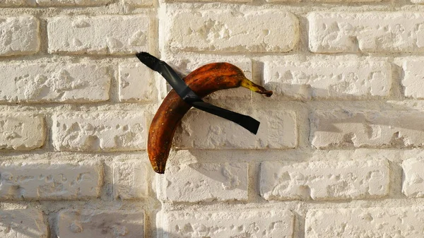 バナナは黒いテープの上の壁に接着されている — ストック写真