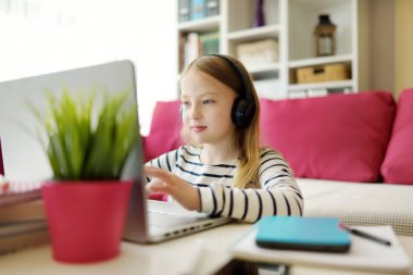 Genç liseli kız evde dijital tabletle ödevini yapıyor. Çocuk çalışmak için aletler kullanıyor. Çocuklar için eğitim ve uzak mesafe eğitimi. Karantina sırasında evde eğitim.