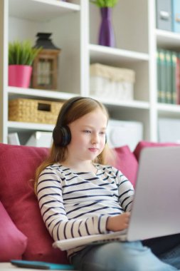 Genç liseli kız evde dijital tabletle ödevini yapıyor. Çocuk çalışmak için aletler kullanıyor. Çocuklar için eğitim ve uzak mesafe eğitimi. Karantina sırasında evde eğitim.