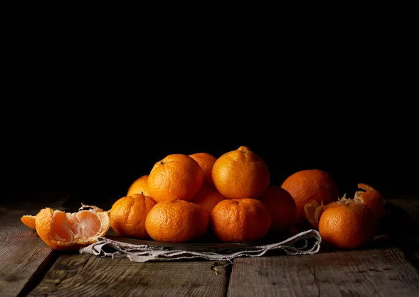 heap of unpeeled round ripe orange mandarin on a gray linen napkin