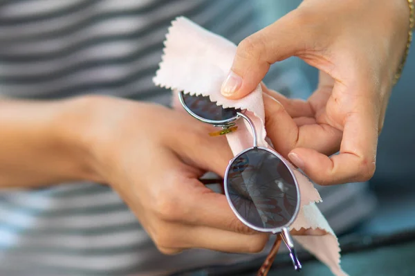マイクロファイバーワイプでサングラスを拭く女性の手 — ストック写真