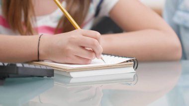 Kız evde ödev yapıyor.