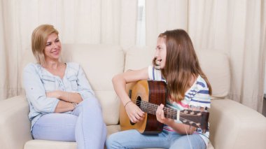 Anne kızına gitar çalmayı öğretiyor.