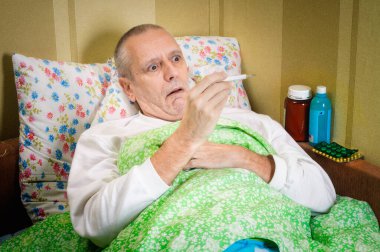 Hasta adam termometreyle yatakta.