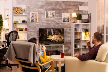 Oturma odasında TV seyreden bir çiftin arka görüntüsü.