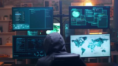 Back view of hooded cyber terrorist using super computer