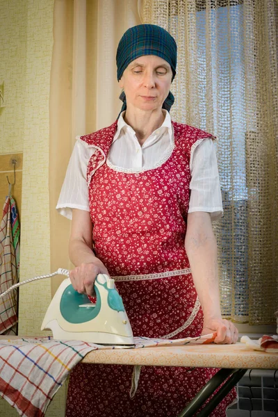 キッチンでアイロンをかける成熟した女性 — ストック写真