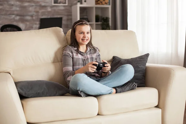 勇敢な小さな女の子は ビデオゲームをプレイするソファに座っています — ストック写真