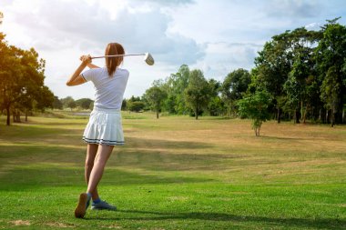 Güzel kız güneşli yeşil golf sahasında golf oynuyor.