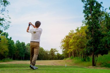 Adam güzel güneşli yeşil golf sahasında golf oynuyor