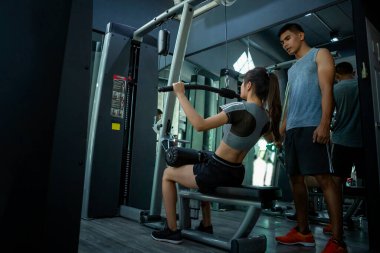 Spor salonunda müşterisiyle egzersiz yapan beden eğitimi öğretmeni.