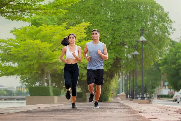 Couples who take care of their health by exercising happily  in the park