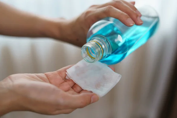 Pouring ethyl alcohol from bottle  into a cotton piece