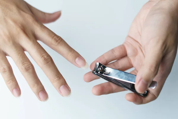 Man using nail clipper clipping her fingernails. white background