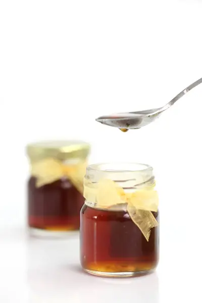 蜂蜜从勺子上滴落在罐子上 在白色背景上隔离 — 图库照片