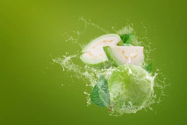 緑の背景に緑のグアバ果物に水が飛び散る — ストック写真