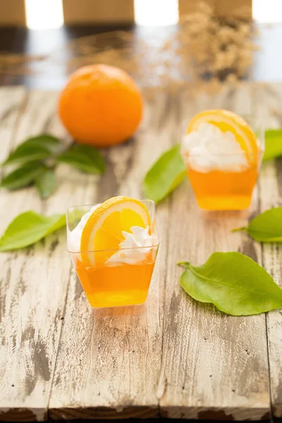 Orange jelly in a cups with whipped cream and orange