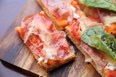 Parma jambonlu pizza roket salatası ve parmesanlı koyu ahşap arka plan. 