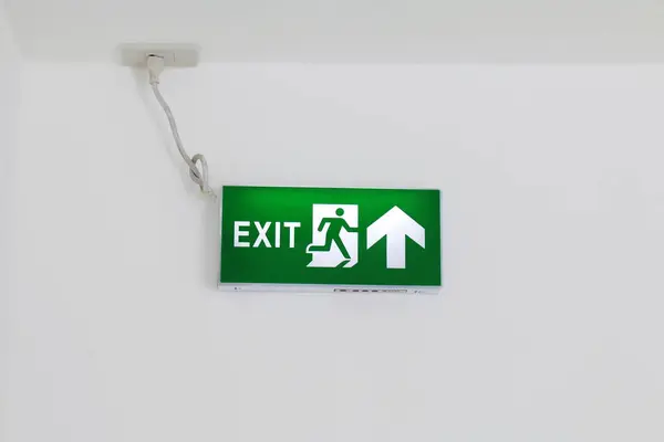 安全最初標識出口標識 避難緑 矢印標識を緑 白い壁 標識緊急ライト ボックスの看板に火します — ストック写真