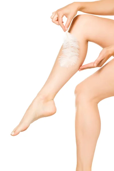 Žena Dotýká Její Krásné Nohy Peřím Bílém Pozadí — Stock fotografie