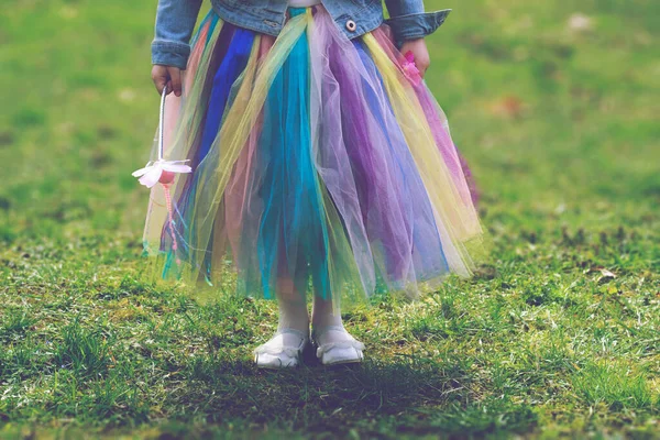 穿着五彩斑斓的短裙站在绿草上的小女孩 — 图库照片