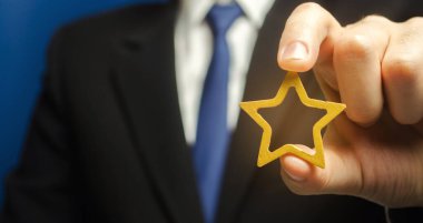 Adam elinde altın bir yıldız tutuyor. Başarı ve mükemmelliğin sembolü. İyi şöhret, prestij, yüksek tanınma. Durum, reyting. Reytingler ve eleştiriler iyi. VIP. İş tanıtımı ve kariyer büyümesi