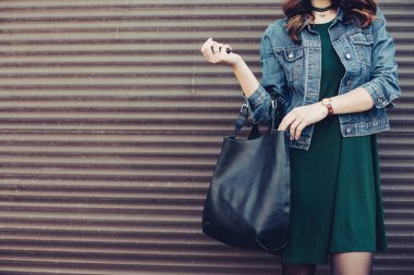 Stylish incognito girl posing at street with black leather bag