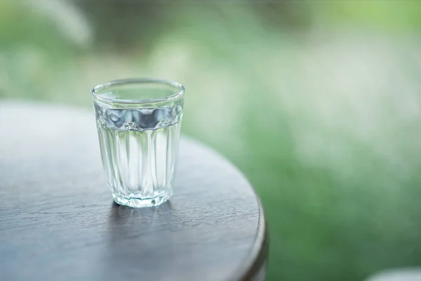 テーブルの上に置かれた水で満たされた小さなガラス — ストック写真