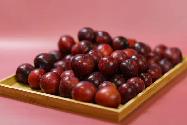 Ameixas Vermelhas Fruta Bandeja Madeira Com Fundo Vermelho — Fotografia de Stock