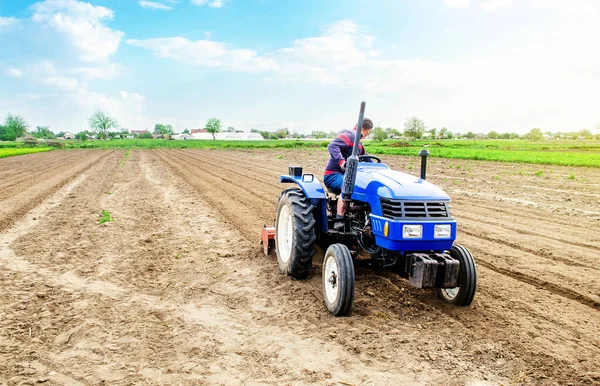 一个农民在田里骑拖拉机 从事农业和农业劳动 耕作土地 以便进一步种植 利用技术促进工作和提高效率 — 图库照片