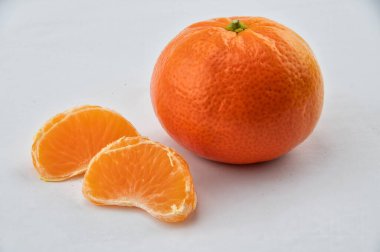 Beyaz arka planda iki meyve segmenti ile clementine meyvesi