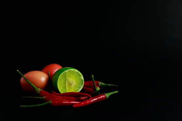 green chili pepper and salt with lime on a black background