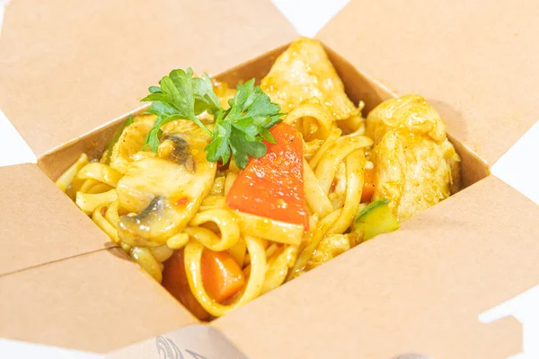 Box of stir fried chicken curry noodle served in a paper box for take away