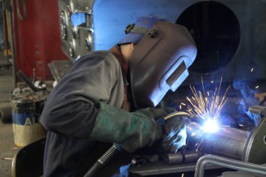 Endüstriyel fabrikada çelikle çalışan kaynakçı