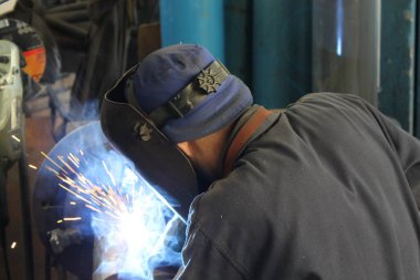 Endüstriyel fabrikada çelikle çalışan kaynakçı