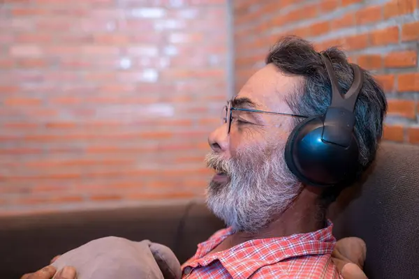 The old man listens to the music from the headphones.