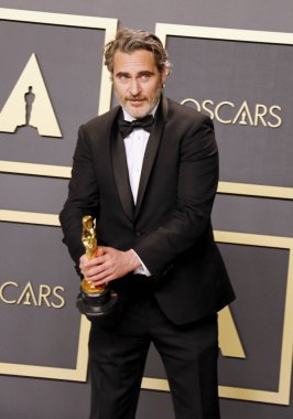 Joaquin Phoenix papyonlu ve siyah takım elbiseli kamera önünde Oscar töreni  