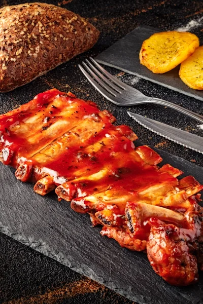 Closeup Baked Pork Ribs Barbecue Sauce Slate Bottom Baked Potatoes — Stockfoto