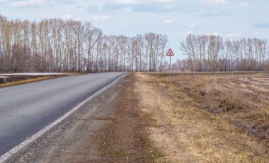 İlkbahar kır yolunda yol işaretleri olan bir yol.