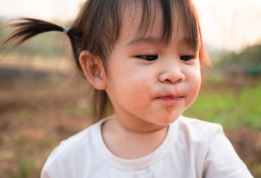 Asyalı küçük kız taze dut toplarının tadını test ediyor bahçede başlıyor, ilk kez yiyor. Oyun, çocuklara öğrenmektir.