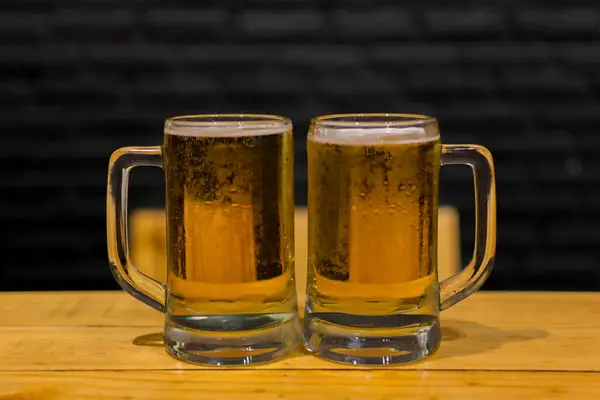 Beer with ice in mugs on background